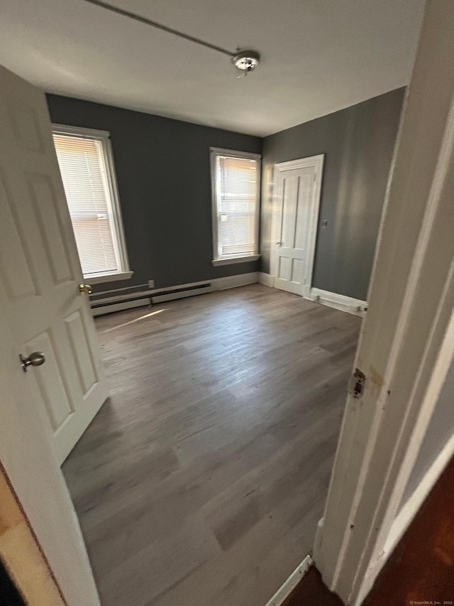 interior space with dark hardwood / wood-style flooring and a baseboard heating unit