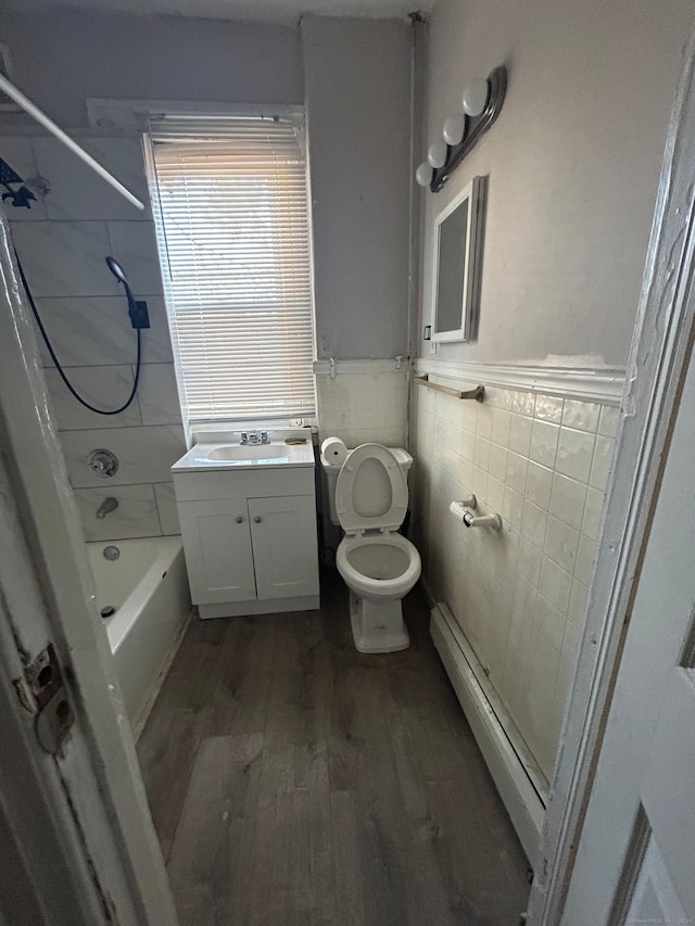 full bathroom with a baseboard heating unit, hardwood / wood-style floors, toilet, vanity, and tile walls