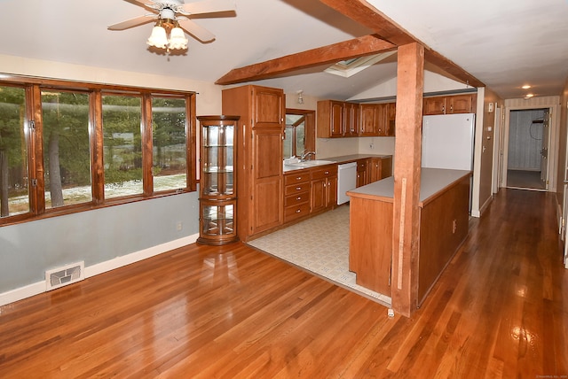 kitchen with white appliances, wood-type flooring, vaulted ceiling with beams, and sink