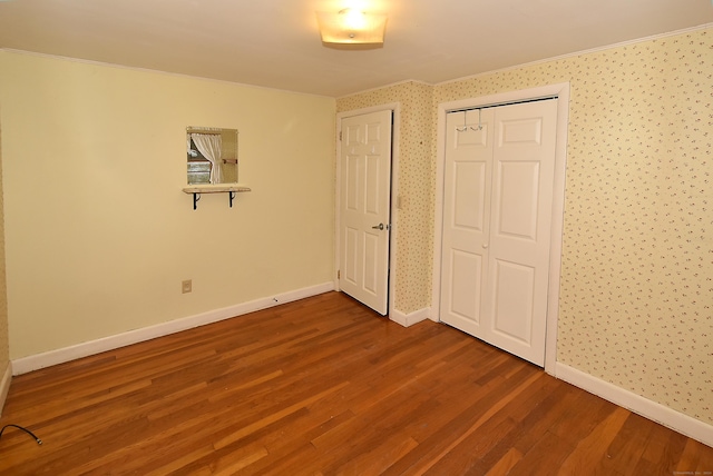 unfurnished bedroom with hardwood / wood-style flooring, crown molding, and a closet