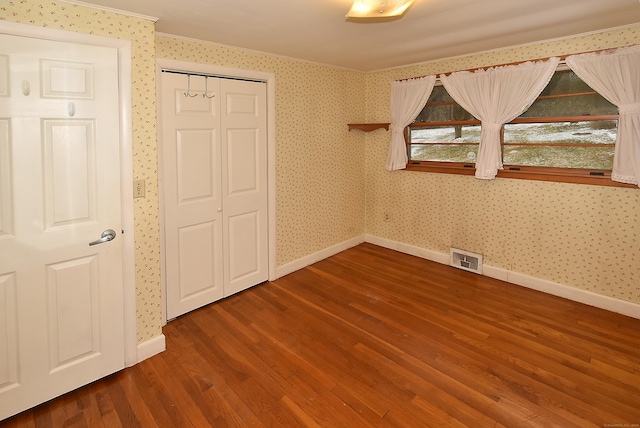 unfurnished bedroom with hardwood / wood-style flooring, a closet, and crown molding