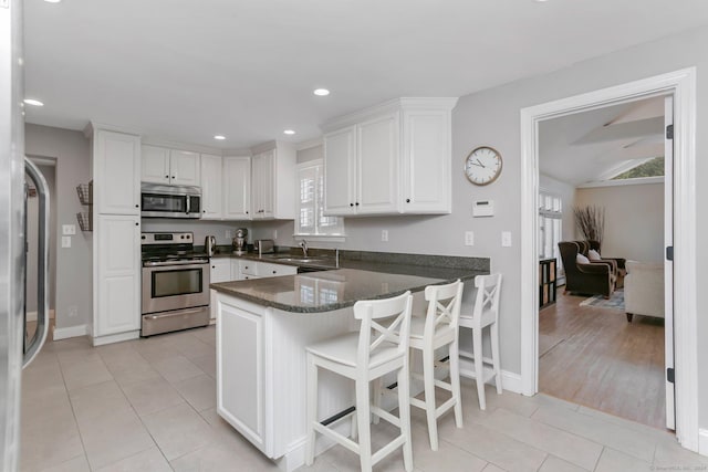 kitchen featuring white cabinetry, light tile patterned floors, stainless steel appliances, and kitchen peninsula