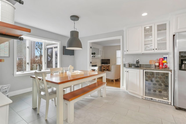 kitchen featuring stainless steel refrigerator with ice dispenser, a healthy amount of sunlight, white cabinets, and beverage cooler