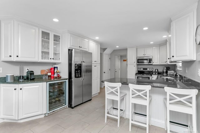 kitchen with sink, appliances with stainless steel finishes, white cabinetry, wine cooler, and kitchen peninsula