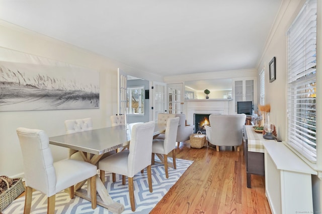 dining area with built in shelves, ornamental molding, french doors, and light wood-type flooring