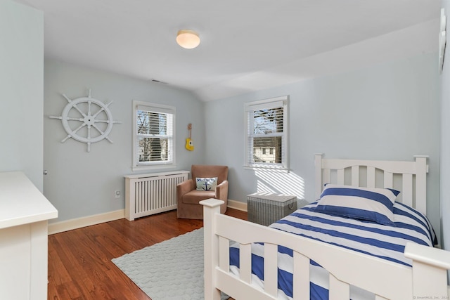 bedroom featuring dark hardwood / wood-style flooring, radiator, and vaulted ceiling