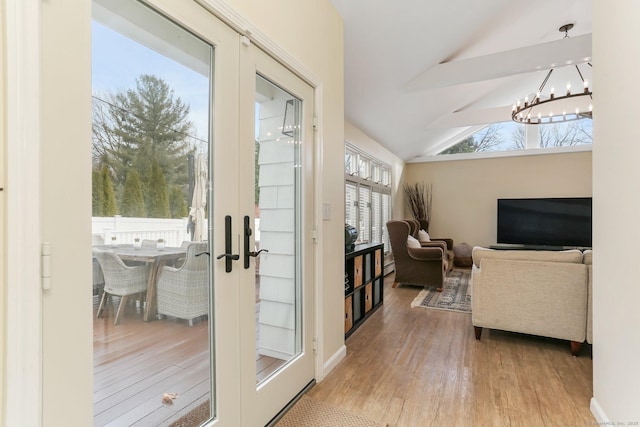 entryway with french doors, lofted ceiling, light wood-type flooring, and a notable chandelier