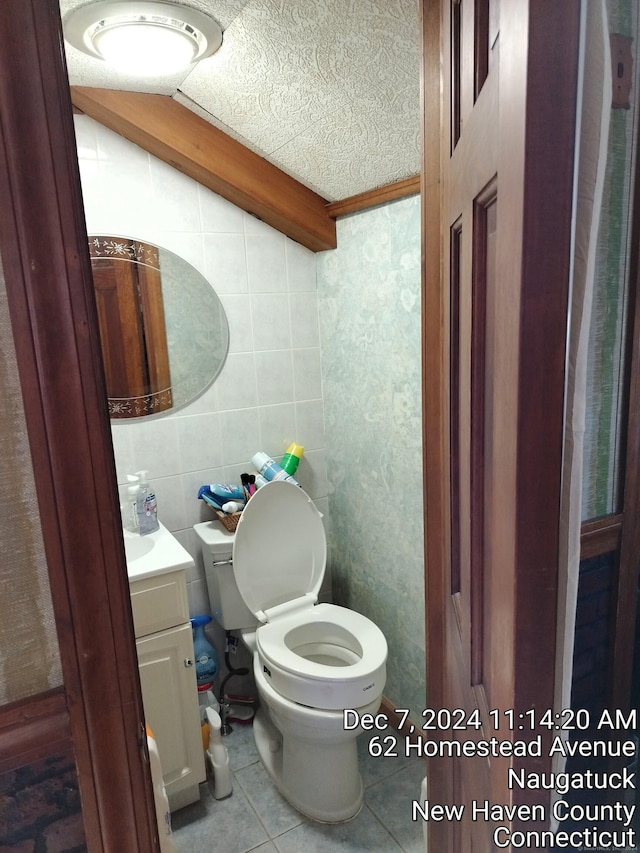 bathroom featuring vanity, tile patterned floors, toilet, a textured ceiling, and tile walls