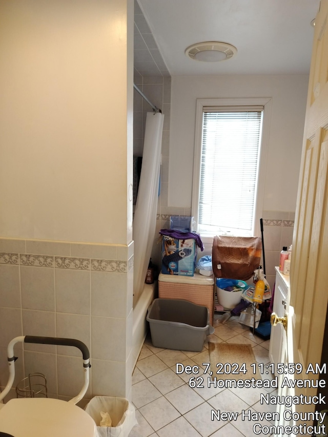 bathroom with tile patterned flooring, shower / tub combo, tile walls, and toilet