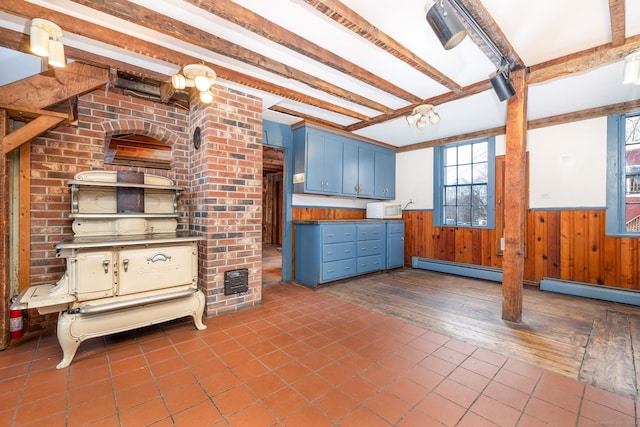 kitchen with blue cabinetry, beamed ceiling, dark hardwood / wood-style floors, a baseboard heating unit, and wood walls