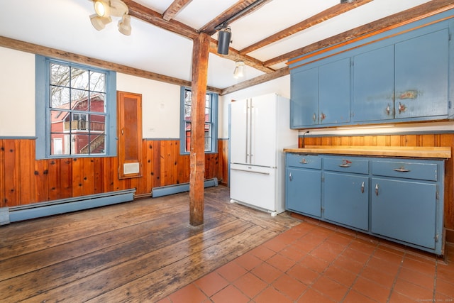 kitchen featuring beam ceiling, wood walls, dark tile patterned flooring, and a baseboard heating unit