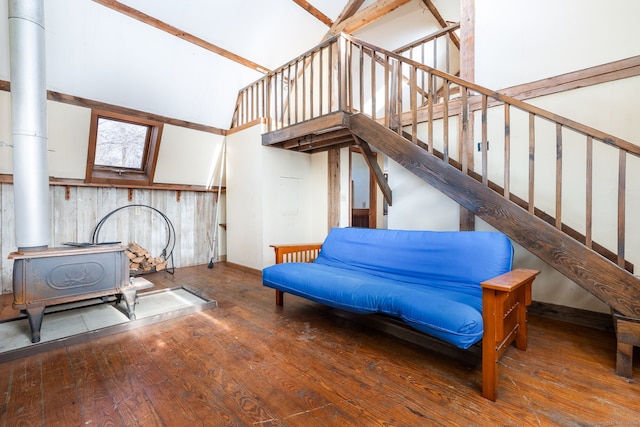 living area with high vaulted ceiling, hardwood / wood-style flooring, a wood stove, and wooden walls