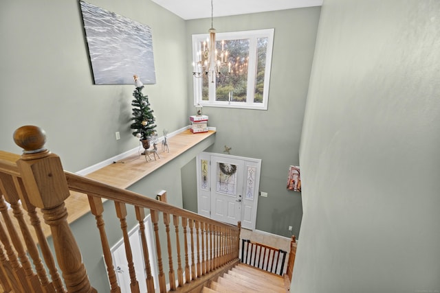 stairway with hardwood / wood-style floors and an inviting chandelier