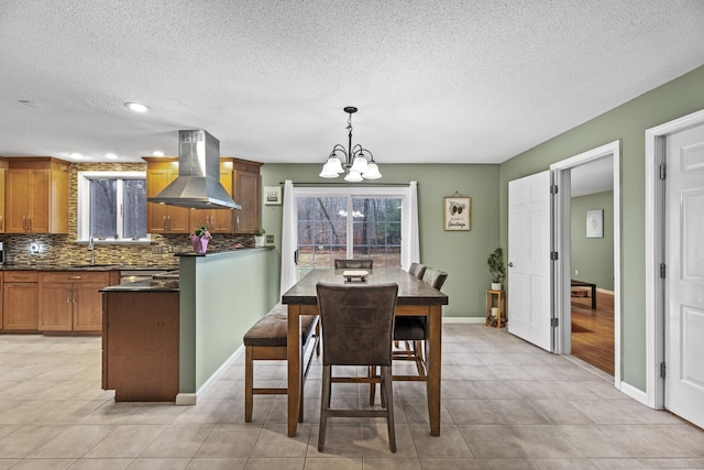 tiled dining area featuring a textured ceiling, sink, and an inviting chandelier