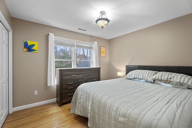 bedroom with a closet, a textured ceiling, and light hardwood / wood-style flooring