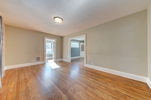 unfurnished room with a textured ceiling and light wood-type flooring