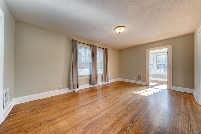 empty room with light hardwood / wood-style flooring and a textured ceiling