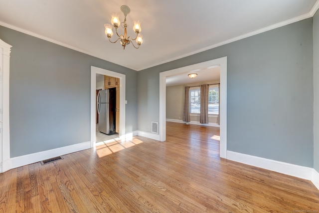 spare room with crown molding, light hardwood / wood-style floors, and a notable chandelier