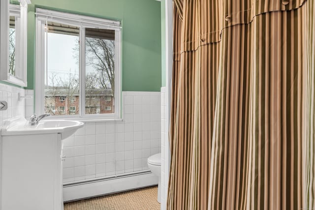 bathroom featuring tile patterned flooring, a baseboard radiator, tile walls, and toilet