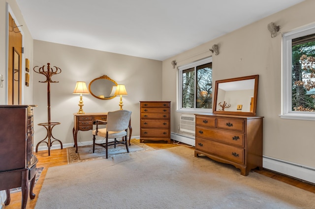 sitting room with a wall unit AC, a wealth of natural light, baseboard heating, and light wood-type flooring