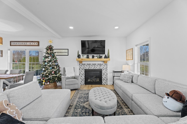 living room with hardwood / wood-style flooring, beam ceiling, a tiled fireplace, and a wealth of natural light