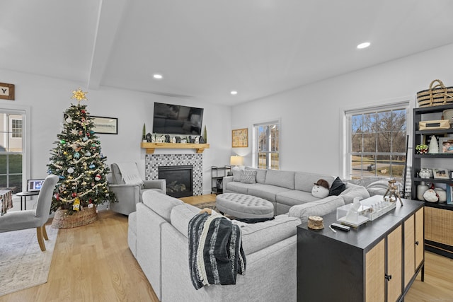 living room with a fireplace, beam ceiling, and light hardwood / wood-style flooring