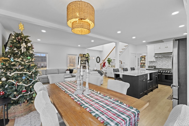 dining room featuring a notable chandelier, beam ceiling, and light wood-type flooring