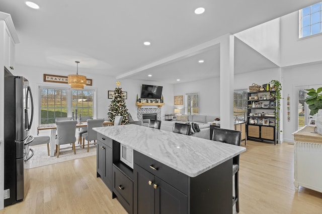 kitchen featuring a kitchen island, pendant lighting, white cabinets, stainless steel fridge, and light hardwood / wood-style floors