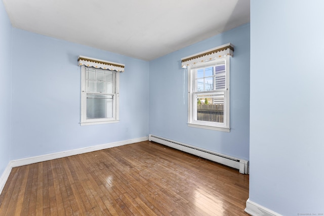 empty room featuring hardwood / wood-style floors and a baseboard radiator