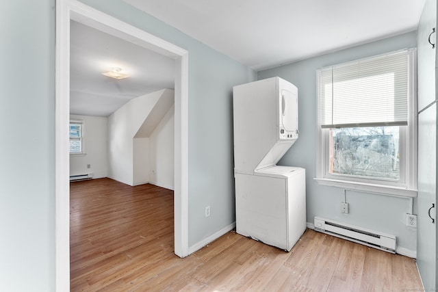 clothes washing area featuring stacked washer and dryer, a baseboard radiator, and light hardwood / wood-style flooring