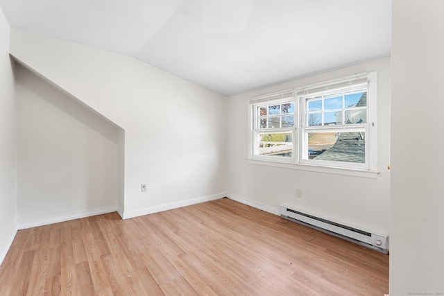 empty room with light hardwood / wood-style floors, lofted ceiling, and a baseboard heating unit