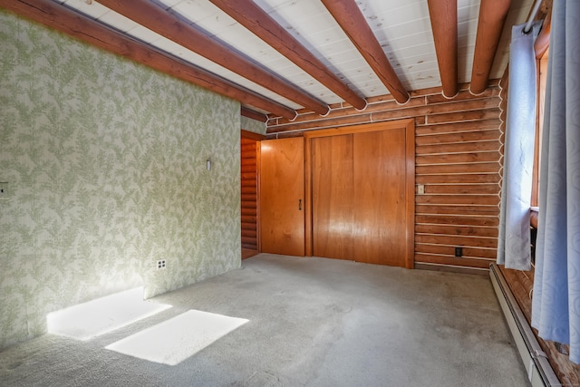 unfurnished bedroom featuring log walls, carpet, baseboard heating, beam ceiling, and a closet