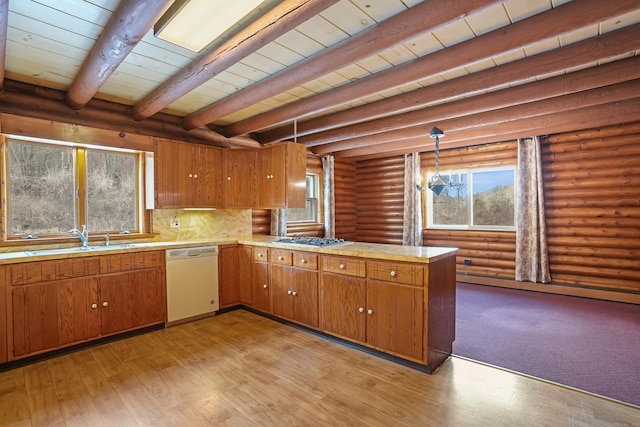 kitchen with stainless steel gas stovetop, sink, hanging light fixtures, white dishwasher, and kitchen peninsula