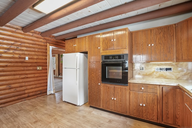 kitchen with black oven, log walls, white refrigerator, beam ceiling, and light hardwood / wood-style flooring