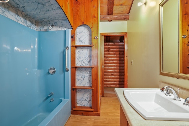 bathroom featuring bathtub / shower combination, vanity, beamed ceiling, log walls, and hardwood / wood-style floors