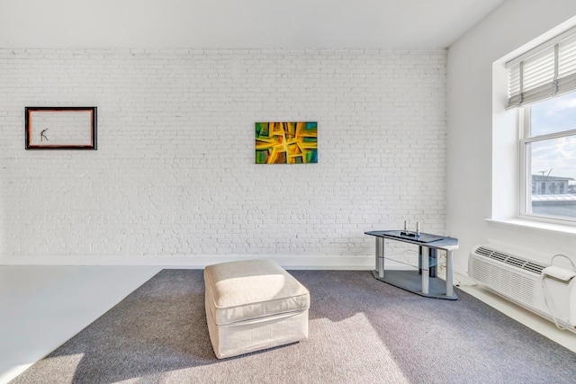 sitting room with a wall unit AC, carpet floors, and brick wall