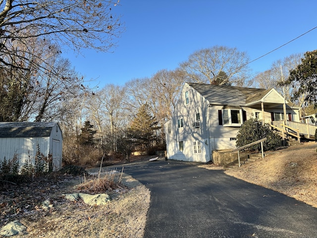 view of property exterior with a storage unit and a wooden deck