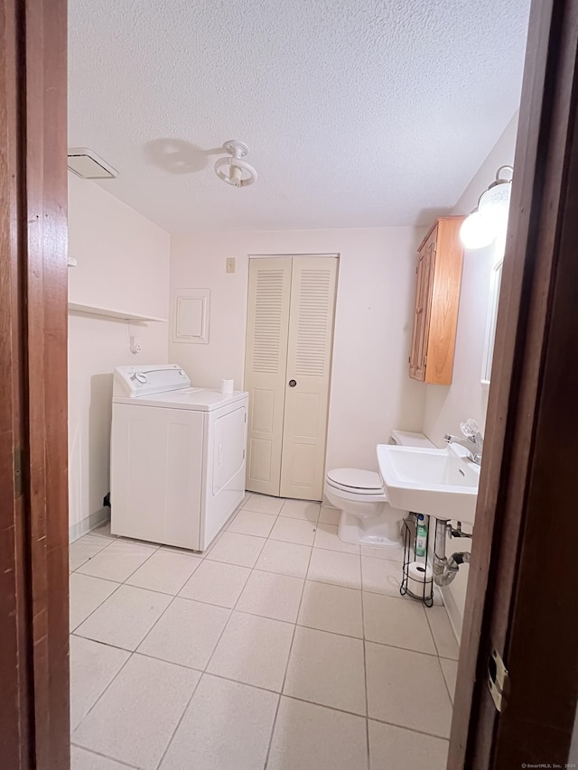 bathroom featuring washer / clothes dryer, tile patterned flooring, a textured ceiling, and toilet