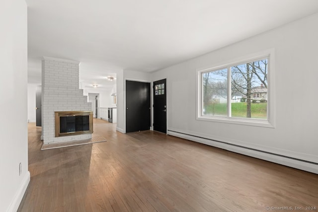 unfurnished living room featuring a fireplace, hardwood / wood-style floors, and a baseboard heating unit