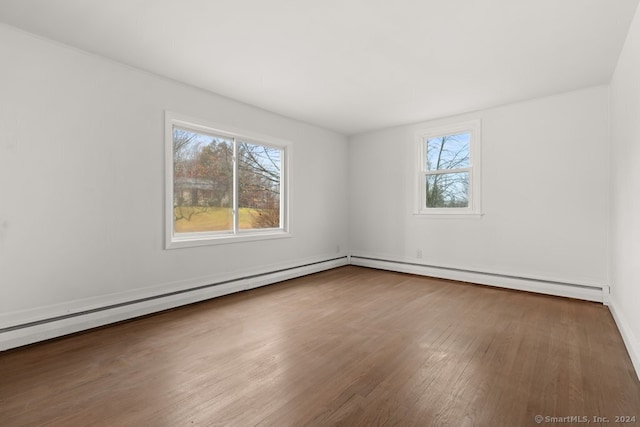 unfurnished room featuring wood-type flooring, a baseboard radiator, and plenty of natural light