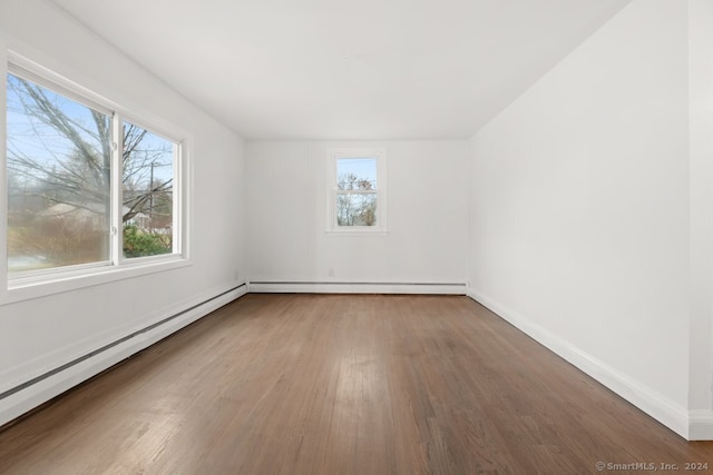 empty room featuring wood-type flooring and baseboard heating