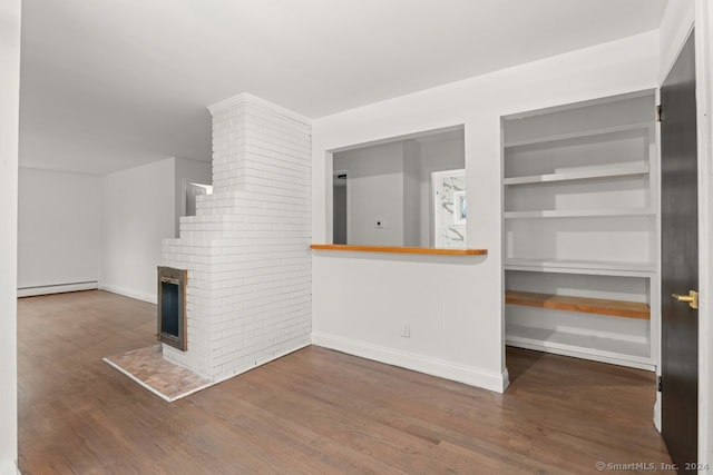 unfurnished living room with built in shelves, a baseboard radiator, a brick fireplace, and dark wood-type flooring