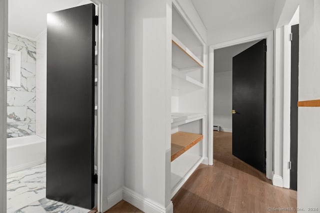 corridor with hardwood / wood-style floors and a baseboard radiator