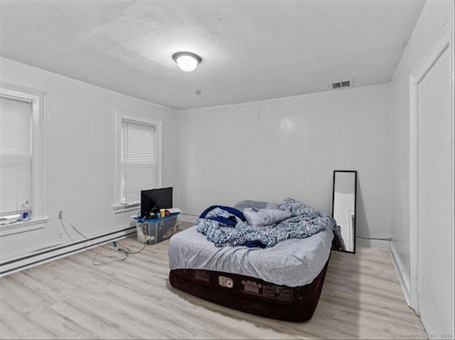 bedroom with light wood-type flooring and a baseboard radiator