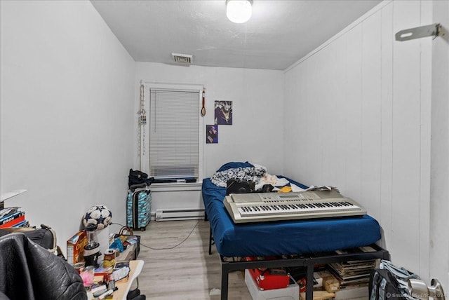 bedroom with a baseboard radiator and light wood-type flooring