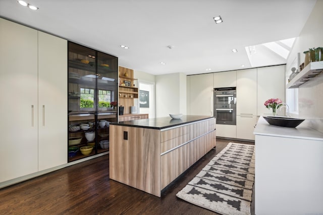 kitchen featuring dark wood-type flooring, sink, white cabinetry, a kitchen island, and stainless steel double oven