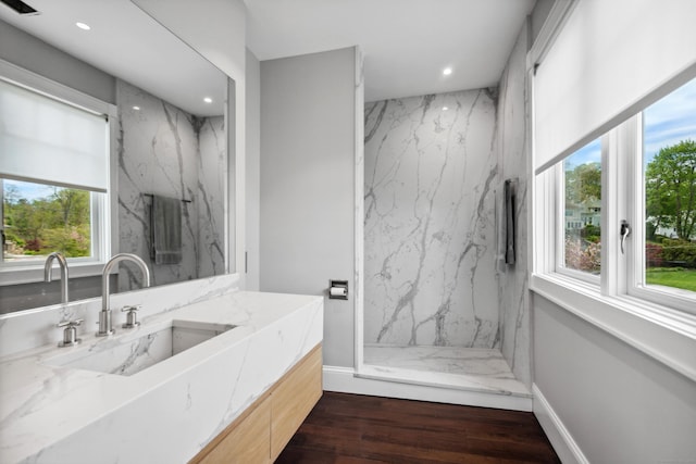 bathroom with vanity, a healthy amount of sunlight, a tile shower, and wood-type flooring