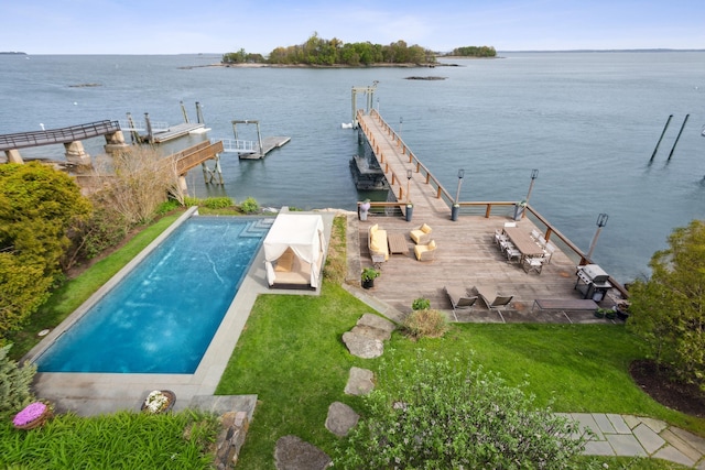 dock area with a patio area, a water view, and a yard