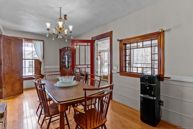 dining space featuring an inviting chandelier, a wealth of natural light, and light hardwood / wood-style flooring