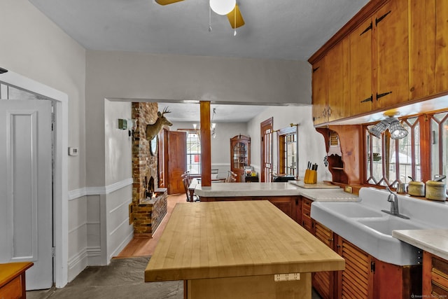 kitchen with kitchen peninsula, ceiling fan, a fireplace, and sink